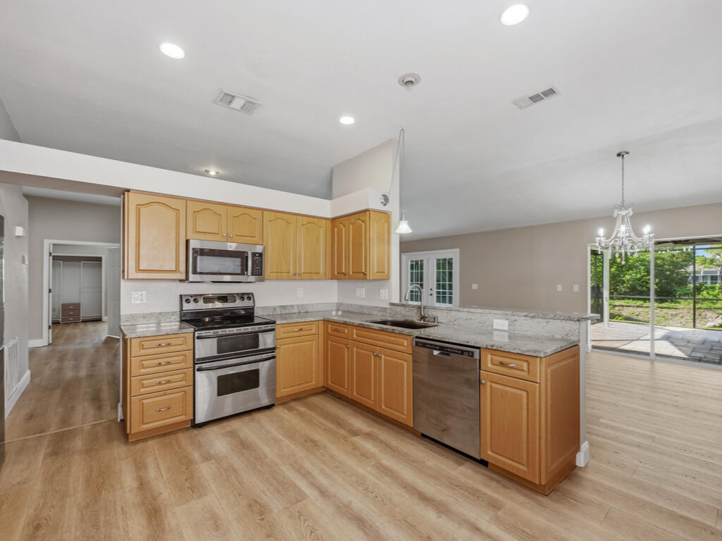 3650 Kent Drive Naples, FL 34112 - Photo 2 of 17 a kitchen with stainless steel appliances granite countertop a stove top oven a sink dishwasher a dining table and chairs with wooden floor