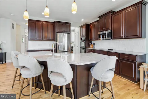 a kitchen with stainless steel appliances granite countertop a refrigerator a sink a stove and a wooden floors