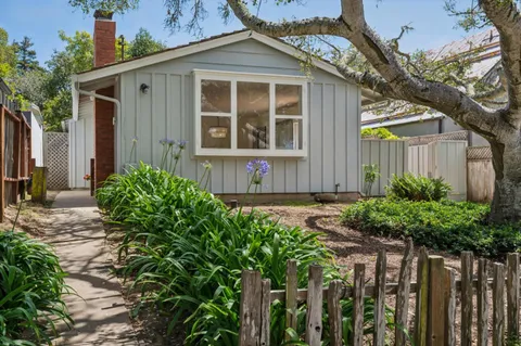 a front view of a house with a yard and potted plants