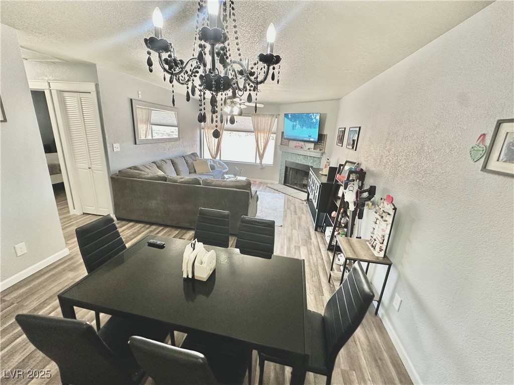 2016 Mesquite Lane, Unit 302 Laughlin, NV 89029 - Photo 12 of 27 Dining space with a fireplace with raised hearth, wood finished floors, a textured ceiling, baseboards, and a textured wall