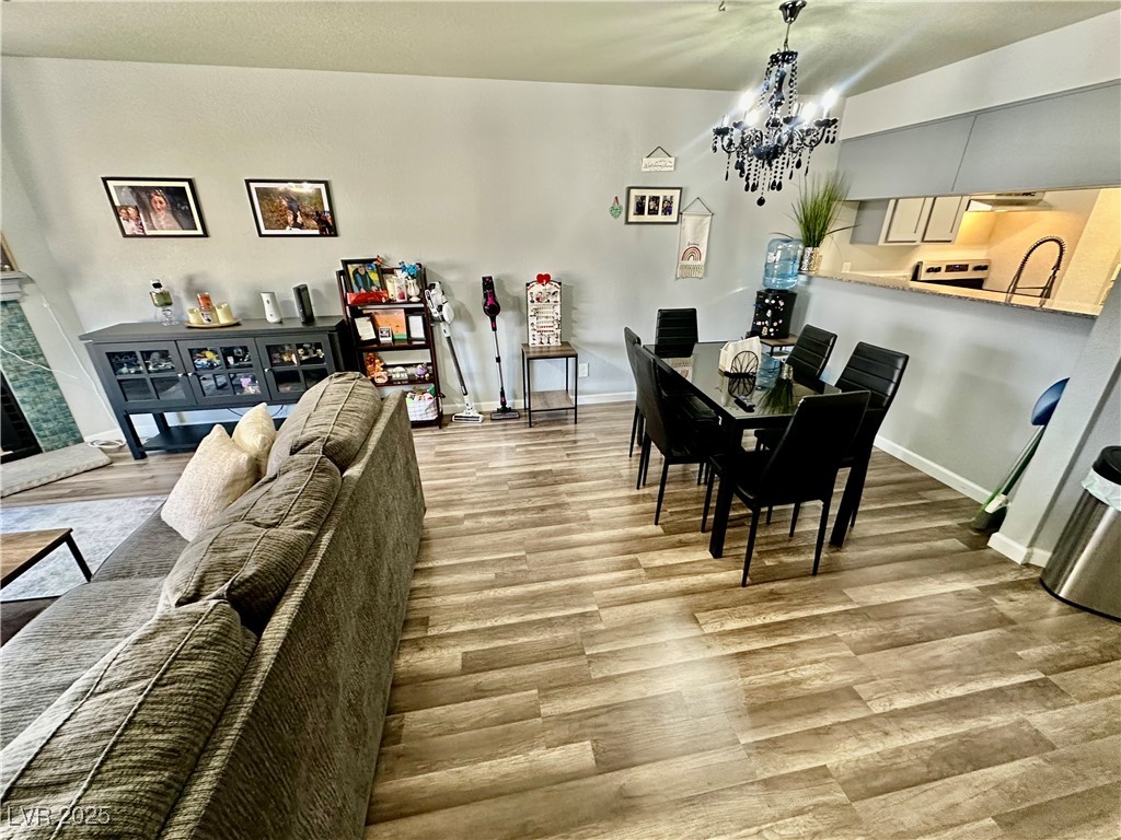 2016 Mesquite Lane, Unit 302 Laughlin, NV 89029 - Photo 6 of 27 Dining area featuring a chandelier, light wood-type flooring, baseboards, and a fireplace with raised hearth