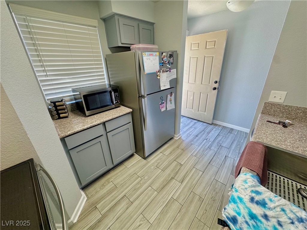 2016 Mesquite Lane, Unit 302 Laughlin, NV 89029 - Photo 8 of 27 Kitchen featuring appliances with stainless steel finishes, light wood finished floors, gray cabinetry, and baseboards