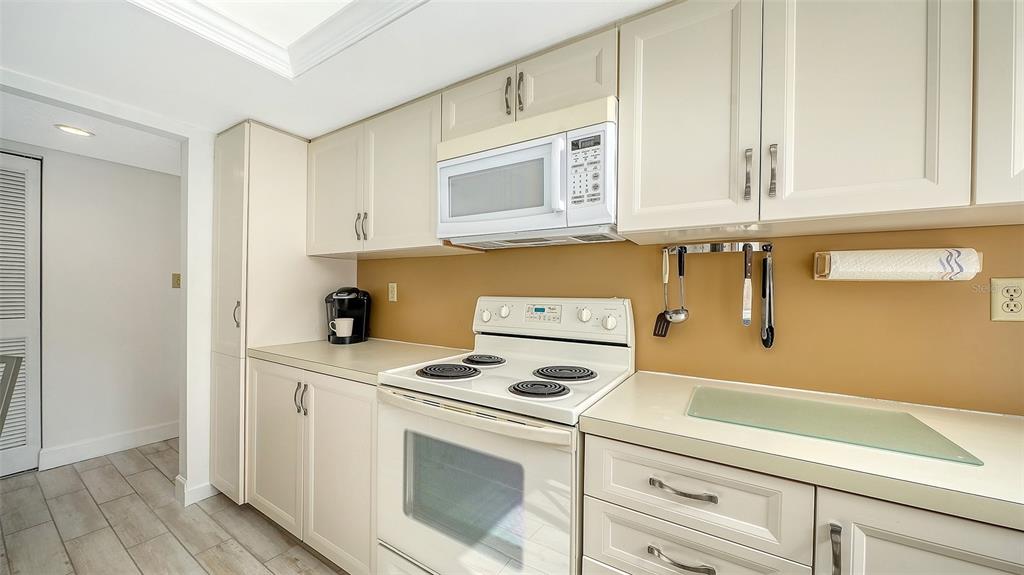 6287 Midnight Pass Road, Unit 103 Sarasota, FL 34242 - Photo 14 of 36 a kitchen with white cabinets and white appliances