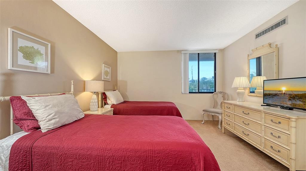 6287 Midnight Pass Road, Unit 103 Sarasota, FL 34242 - Photo 20 of 36 a bedroom with a bed and a flat screen tv