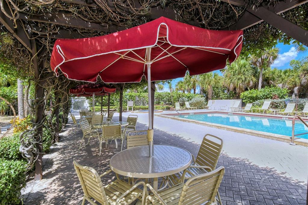 6287 Midnight Pass Road, Unit 103 Sarasota, FL 34242 - Photo 26 of 36 a patio with a table and chairs under an umbrella