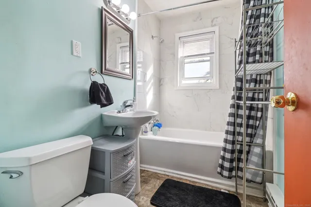 a white toilet sitting next to a bath tub