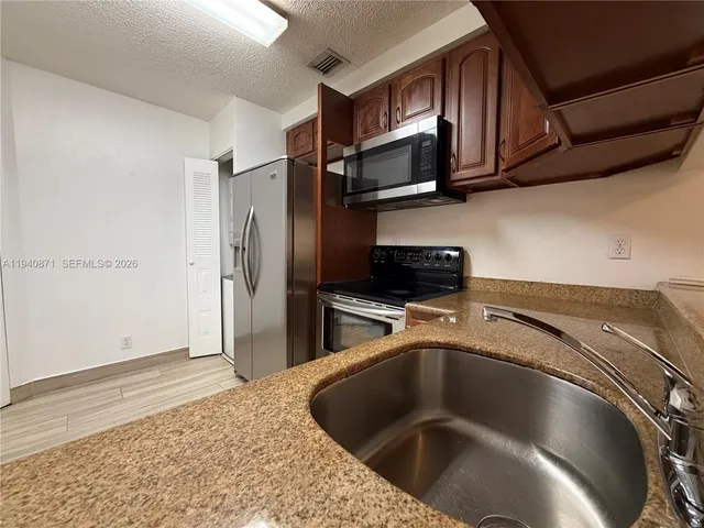 a kitchen with stainless steel appliances granite countertop a refrigerator a stove top oven a sink and dishwasher