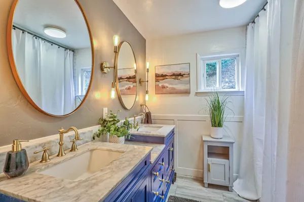 a bathroom with a granite countertop sink a mirror and a potted plant