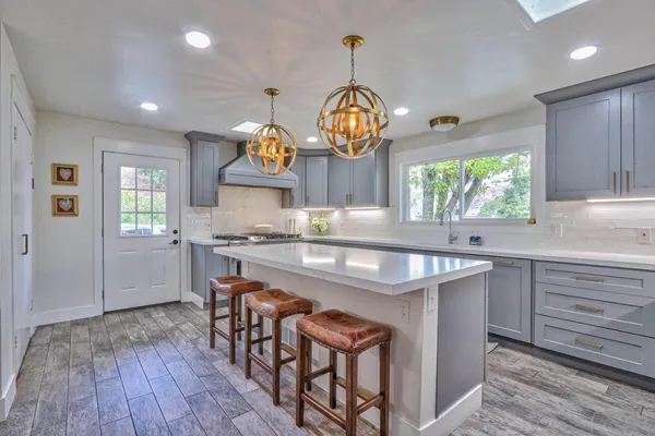 a kitchen with stainless steel appliances granite countertop a stove a sink dishwasher a dining table and chairs with wooden floor