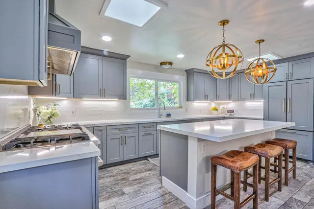 a kitchen with stainless steel appliances granite countertop a sink a stove and a wooden floors