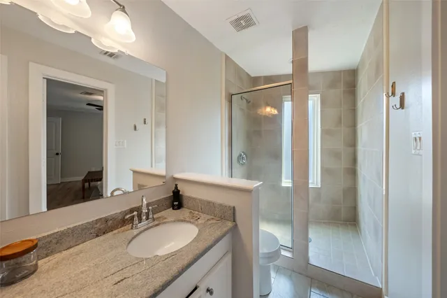 a bathroom with a granite countertop sink a mirror and a shower