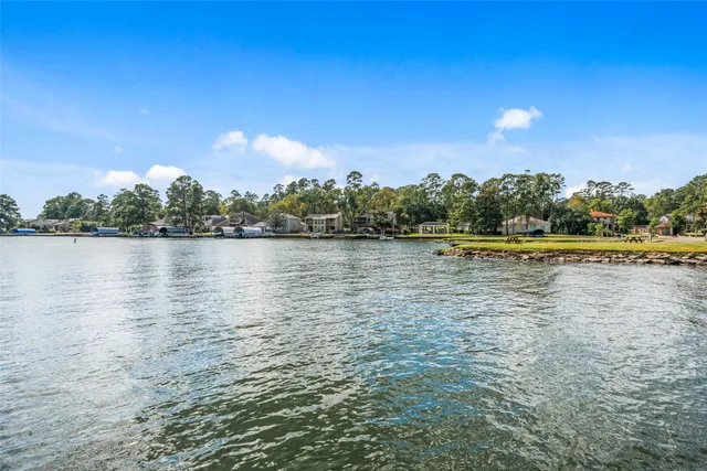 a large kitchen with stainless steel appliances kitchen island granite countertop a refrigerator a sink dishwasher a stove and white countertops with wooden floor