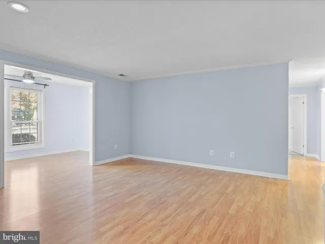 a view of an empty room with wooden floor fireplace and a window