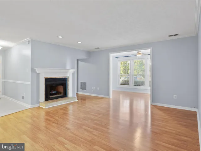 a view of an empty room with wooden floor fireplace and a window