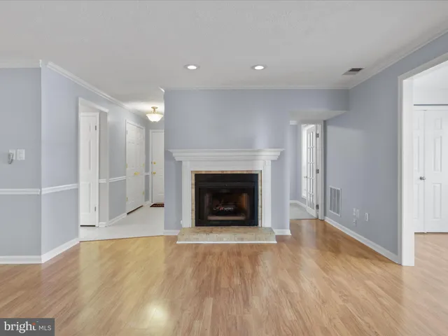 a view of an empty room with wooden floor fireplace and a window