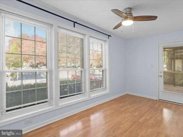 an empty room with wooden floor fireplace and windows