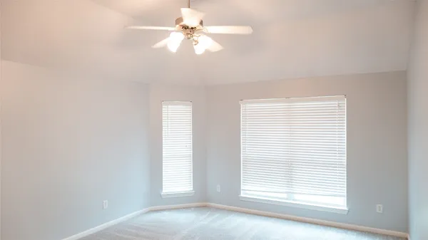 an empty room with windows and fan