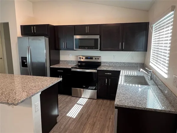 a kitchen with granite countertop stainless steel appliances a stove sink and microwave