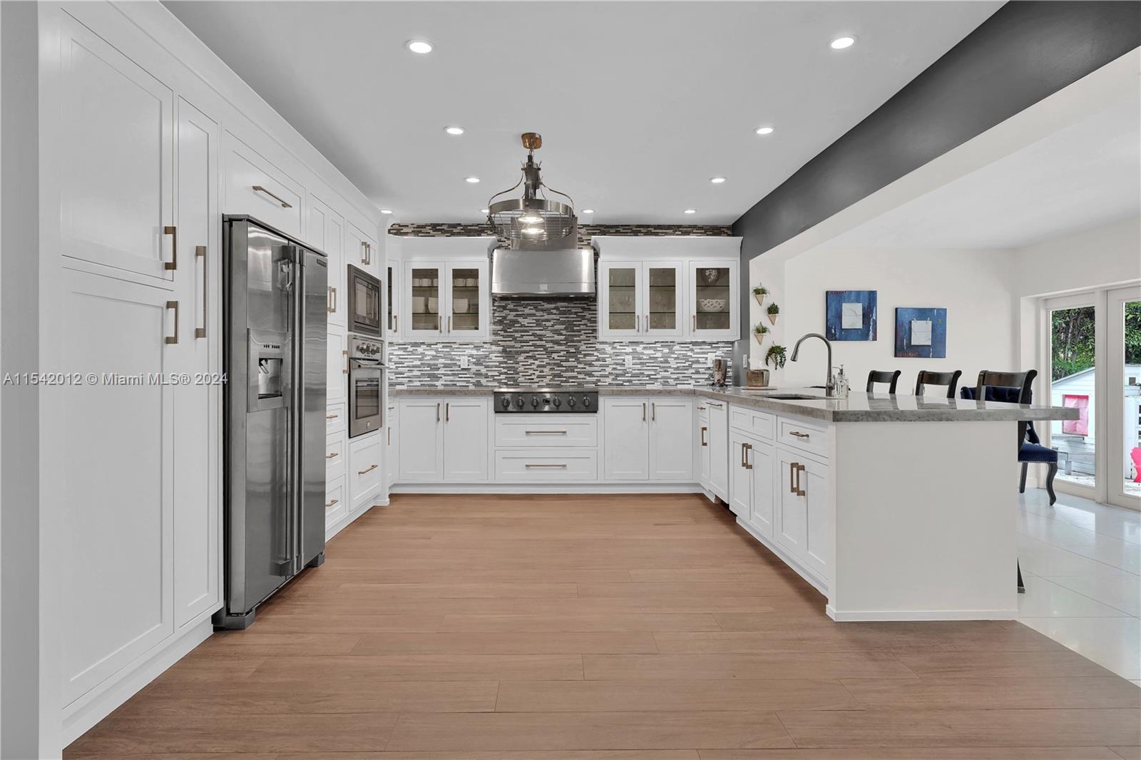 a large white kitchen with stainless steel appliances kitchen island a large counter top and a refrigerator