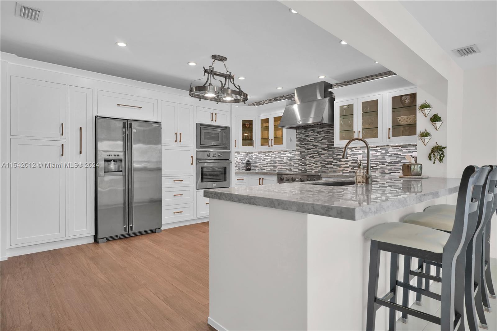 a large kitchen with kitchen island granite countertop a refrigerator and cabinets