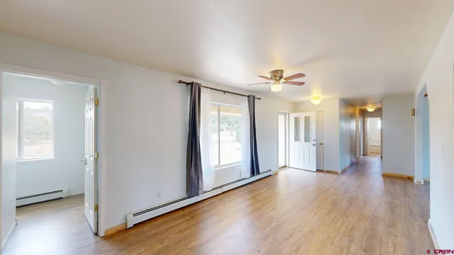 a view of a big room with wooden floor and windows