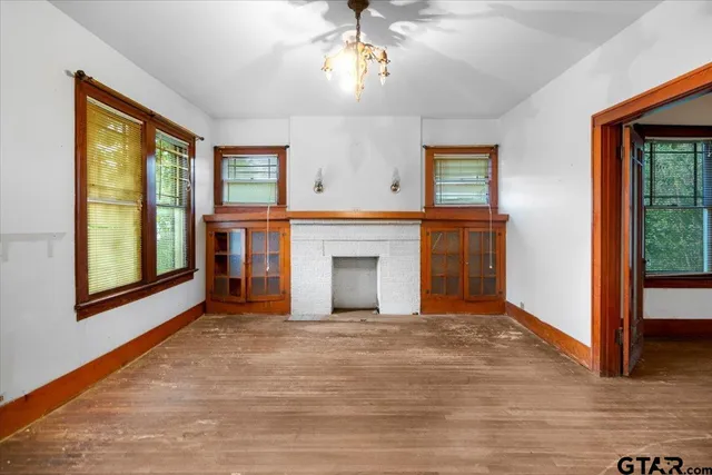 a view of an empty room with window and wooden floor