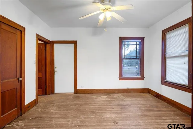an empty room with wooden floor closet and windows