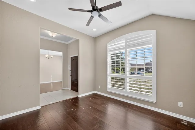 a view of an empty room with a window and wooden floor
