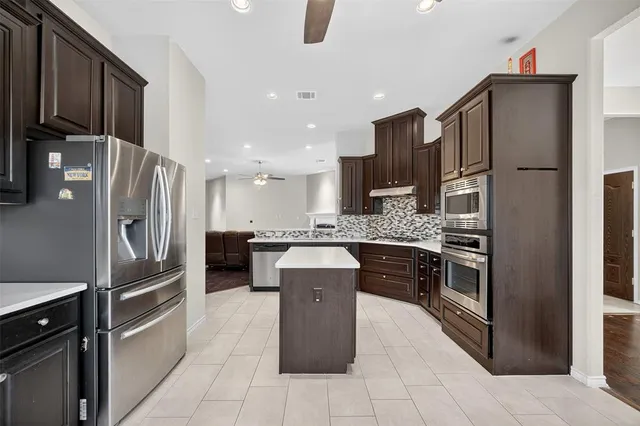 a kitchen with stainless steel appliances granite countertop a refrigerator and a stove top oven