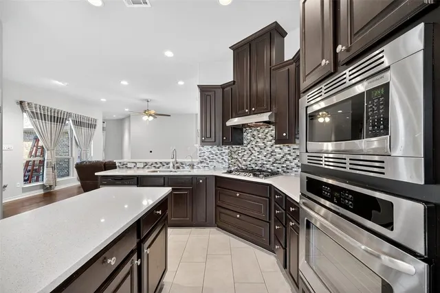 a large kitchen with stainless steel appliances a sink dishwasher a refrigerator and cabinets with wooden floor