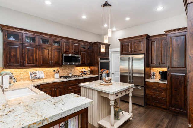 1132 Sunset Dunes Way Draper, UT 84020 - Photo 4 of 35 Kitchen featuring dark wood cabinetry with crown molding, light-colored speckled countertops, stainless steel appliances, a gas cooktop, and wood-finish flooring