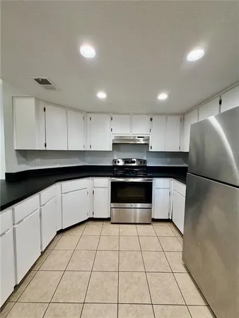 a kitchen with granite countertop a stove a sink and a refrigerator