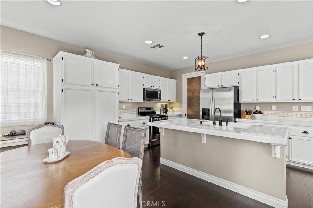 28409 Connick Place Saugus, CA 91350 - Photo 17 of 66 a kitchen with stainless steel appliances kitchen island granite countertop a sink dishwasher a stove a refrigerator with a dining table and chairs