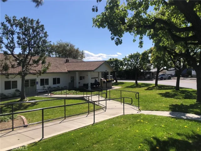 a front view of a building with a garden and trees