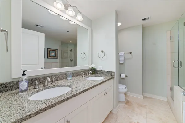a bathroom with a granite countertop double vanity sink and mirror