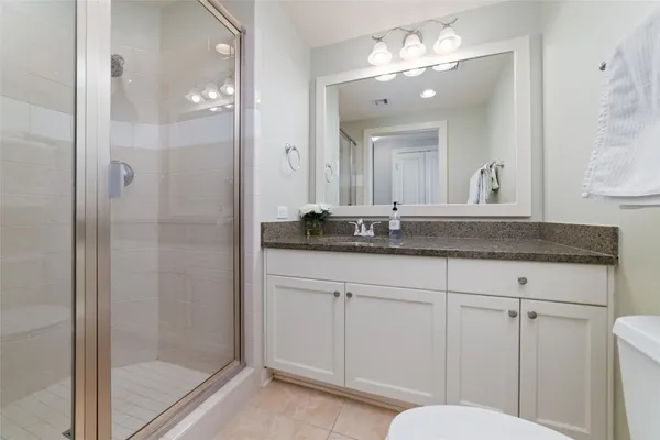 a bathroom with a granite countertop sink a mirror and a shower