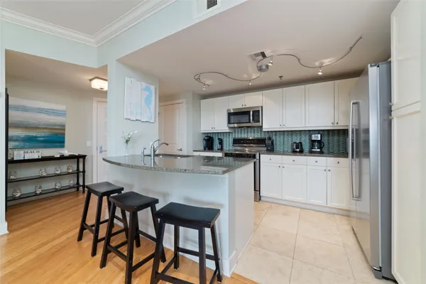 a kitchen with stainless steel appliances granite countertop a stove top oven a sink dishwasher and a refrigerator with wooden floor