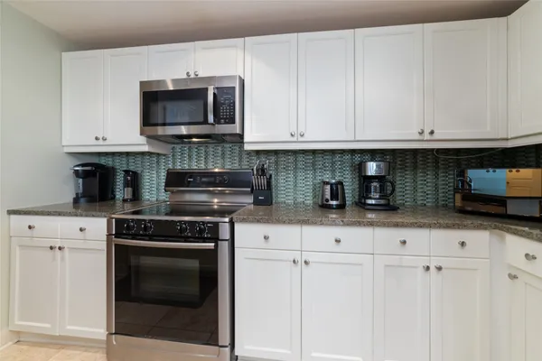 a kitchen with white cabinets and appliances