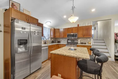 a kitchen with stainless steel appliances granite countertop a refrigerator a stove a sink a dining table and chairs