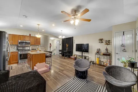 a living room with furniture a flat screen tv and kitchen view