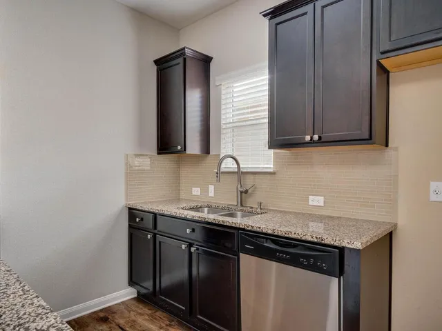 a kitchen with granite countertop a sink cabinets and stainless steel appliances