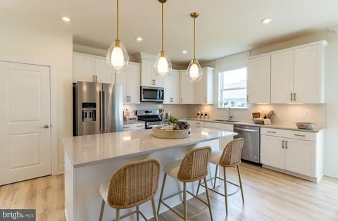 a kitchen with stainless steel appliances granite countertop a sink a stove a refrigerator cabinets and a dining table