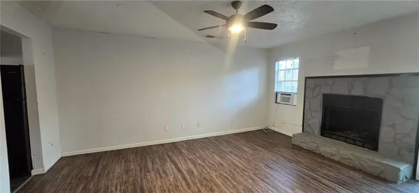 an empty room with wooden floor fireplace and windows