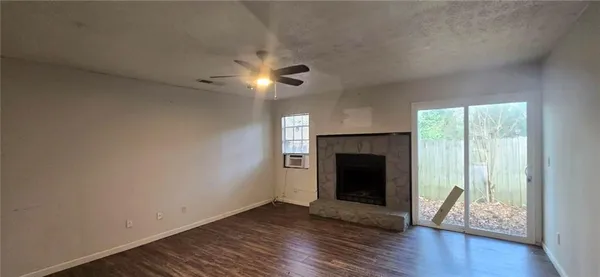 a view of an empty room with wooden floor fireplace and a window