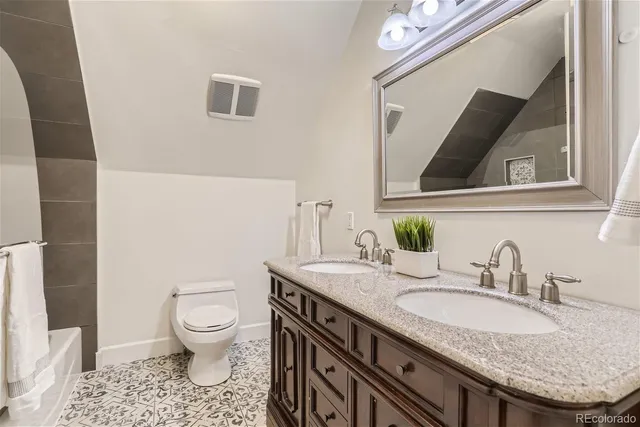 a bathroom with a granite countertop toilet sink and mirror
