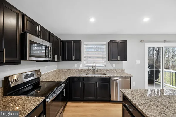 a kitchen with stainless steel appliances granite countertop a stove a sink and a microwave