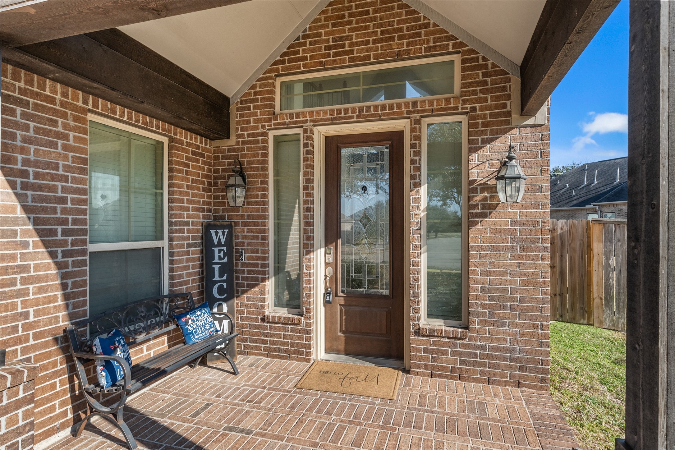 4747 Abercorn Street Rosharon, TX 77583 - Photo 3 of 46 This inviting entryway features a brick facade and a charming wooden door with decorative glass. Flanked by sidelights and a transom window, it offers ample natural light. A cozy bench and welcoming decor add warmth, while overhead beams and lantern-style lighting enhance the home's curb appeal.