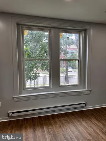 a view of an empty room with a window and wooden floor