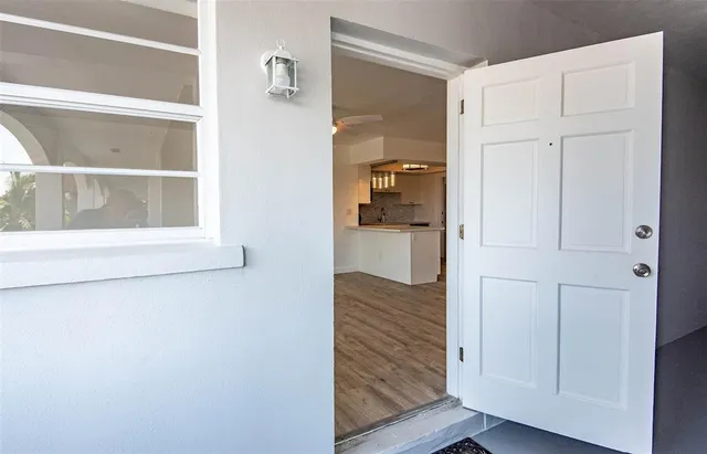 a view of empty room with wooden floor and kitchen