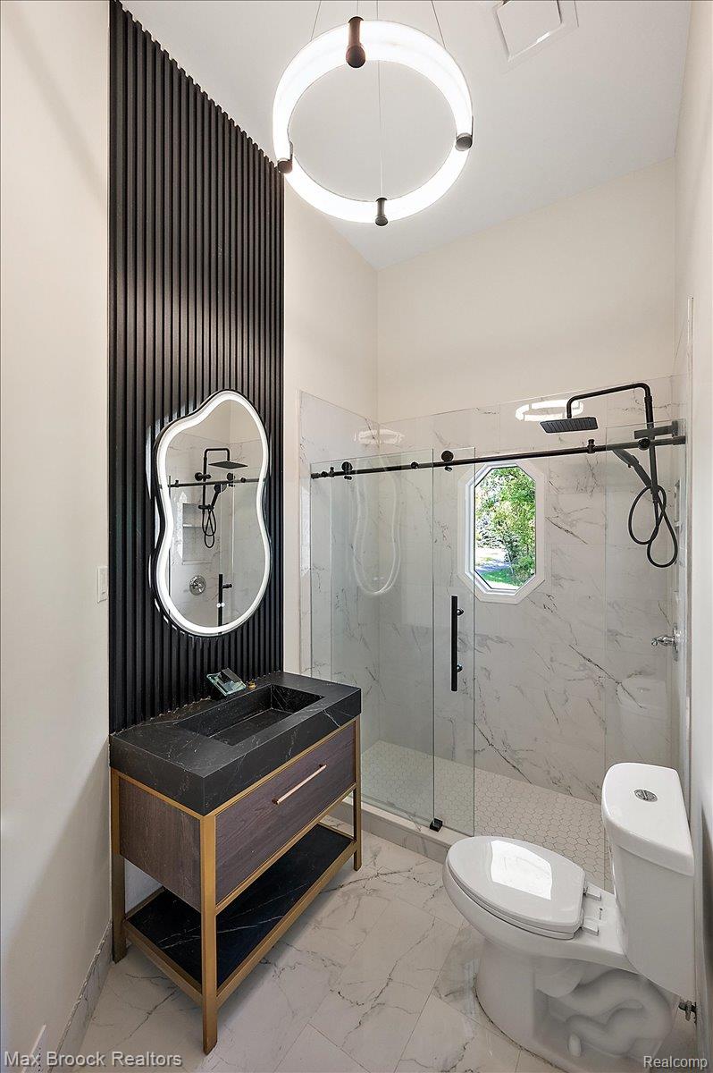 4597 Clarkston Road Clarkston, MI 48348 - Photo 29 of 74 Vanity with integrated basin, black slatted accent wall, circular pendant light fixture, glass-enclosed shower, and octagonal window